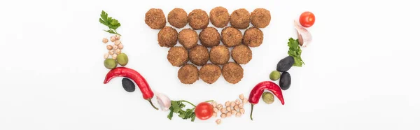 Blick von oben auf Kichererbsen, Knoblauch, Kirschtomaten, Petersilie, Oliven, Chilischote, grüne Zwiebeln, lächelnd neben Falafel-Bällchen auf weißem Hintergrund angeordnet, Panoramaaufnahme — Stockfoto