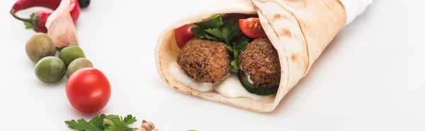 Close up view of vegetables arranged in round frame around falafel in pita on white background, panoramic shot — Stock Photo