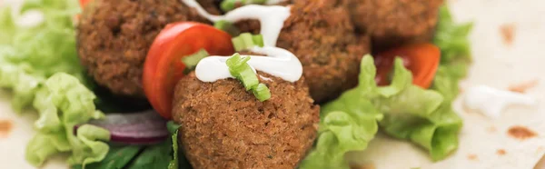 Vue rapprochée des boules de falafel fraîches sur pita aux légumes et sauce, panoramique — Photo de stock