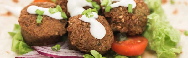 Close up view of fresh falafel balls on pita with vegetables and sauce, panoramic shot — Stock Photo