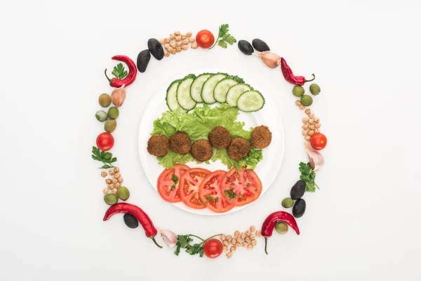 Vista dall'alto di verdure disposte in cornice rotonda intorno a falafel su piatto su sfondo bianco — Foto stock