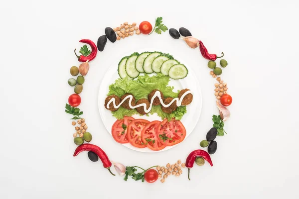 Draufsicht auf Gemüse in rundem Rahmen um Falafel mit Sauce auf Teller auf weißem Hintergrund angeordnet — Stockfoto