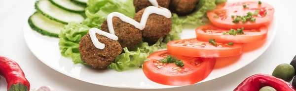 Primer plano vista de falafel con salsa en el plato con verduras en rodajas sobre fondo blanco, plano panorámico - foto de stock