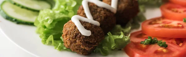 Nahaufnahme von Falafel mit Sauce auf Teller mit Gemüsescheiben auf weißem Hintergrund, Panoramaaufnahme — Stockfoto