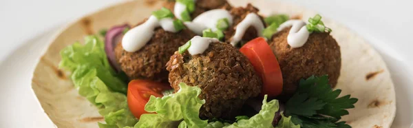 Vue rapprochée de falafel à la sauce sur pita aux légumes en assiette blanche, panoramique — Photo de stock