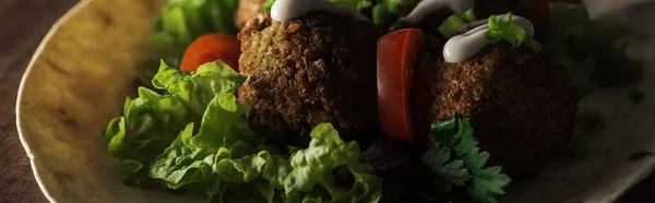 Vista ravvicinata del falafel con salsa sulla pita con verdure al buio, colpo panoramico — Foto stock