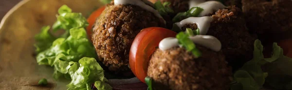 Vista ravvicinata del falafel con salsa sulla pita con verdure al buio, colpo panoramico — Foto stock