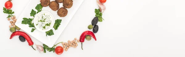 Draufsicht auf Gemüse in rundem Rahmen um Falafel auf Teller mit Soße auf weißem Hintergrund angeordnet, Panoramaaufnahme — Stockfoto