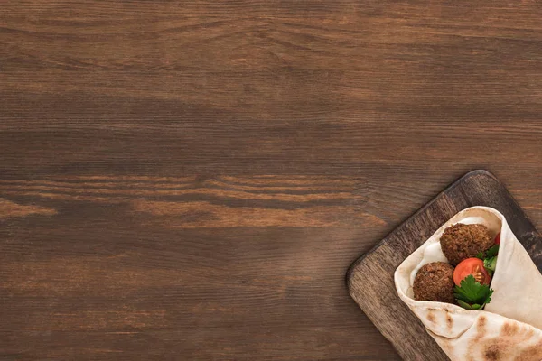Vue du dessus de falafel aux légumes et sauce en pita sur table en bois — Photo de stock