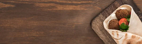 Top view of falafel with vegetables and sauce in pita on wooden table, panoramic shot — Stock Photo