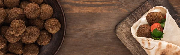 Top view of falafel with vegetables and sauce in pita on wooden table, panoramic shot — Stock Photo