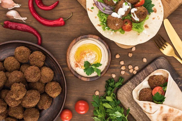 Top view of falafel with vegetables and hummus on wooden table — Stock Photo