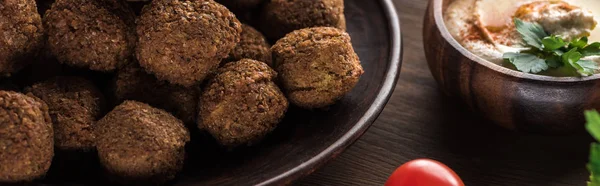 Close up view of falafel balls near hummus on wooden table, panoramic shot — Stock Photo