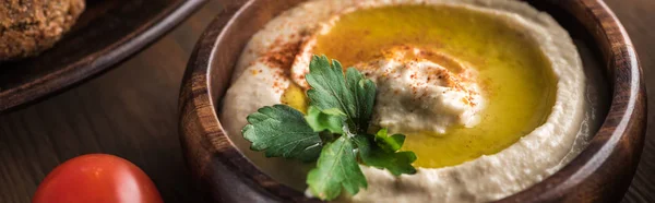 Close up view of delicious falafel balls near hummus with parsley on wooden table, panoramic shot — Stock Photo