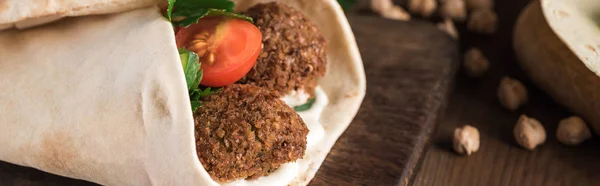 Nahaufnahme von Falafel mit Gemüse und Soße in Fladenbrot gewickelt auf Holztisch, Panoramaaufnahme — Stockfoto