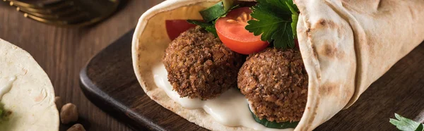 Vista de perto de falafel com verduras e molho em pita na mesa de madeira, tiro panorâmico — Fotografia de Stock