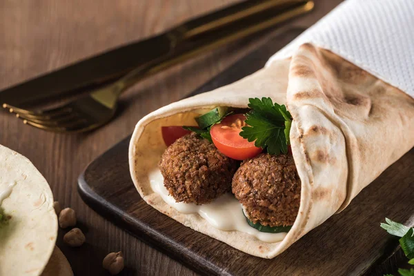 Close up view of falafel with vegetables and sauce in pita on wooden table — Stock Photo