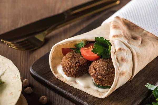 Vue rapprochée de falafel aux légumes et sauce en pita sur table en bois — Photo de stock