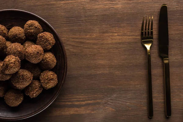 Top view of falafel balls on plate near cutlery on wooden table — Stock Photo