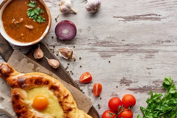 Top view of soup kharcho with Aadjarian khachapuri and vegetables on table — Stock Photo