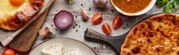 Aadjarian and imereti khachapuri, khinkali and soup kharcho on wooden texture, panoramic shot — Stock Photo