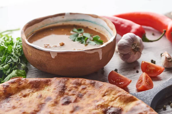 Imereti khachapuri and soup kharcho with cilantro and vegetables on table — Stock Photo