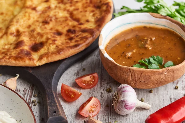 Imereti khachapuri and soup kharcho with spices and vegetables on table — Stock Photo