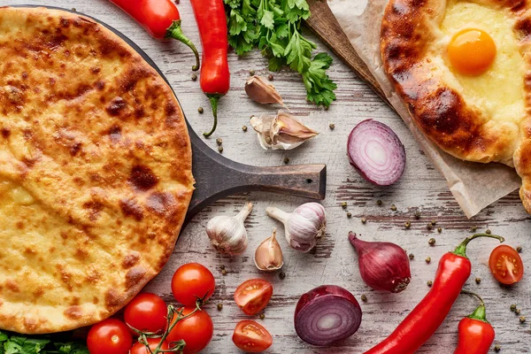 Top view of Imereti and adjarian khachapuri with vegetables, spices and cilantro on table — Stock Photo