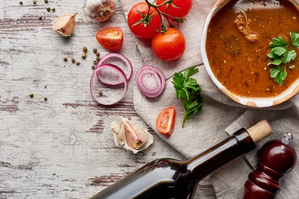 Blick von oben auf Suppe kharcho, Weinflasche, Gemüse und Gewürze auf dem Tisch — Stockfoto