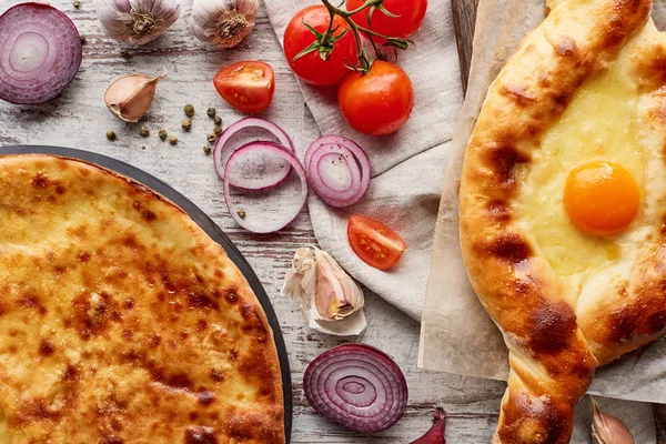 Traditionelle georgische imereti und adjarianische khachapuri mit Gemüse auf dem Tisch — Stockfoto