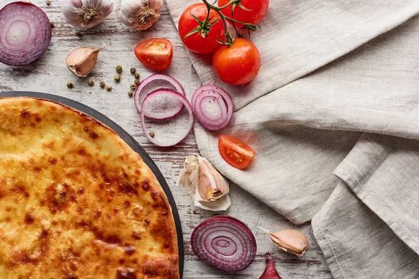 Top view of Georgian imereti khachapuri with vegetables and cloth on table — Stock Photo