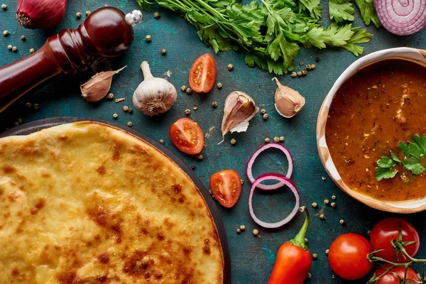 Soup kharcho and imereti khachapuri with spices and vegetables on textured green background — Stock Photo