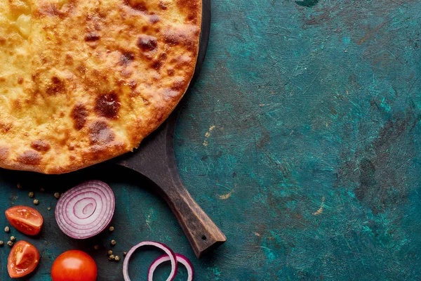 Vista dall'alto di imereti khachapuri con verdure su sfondo verde strutturato — Foto stock