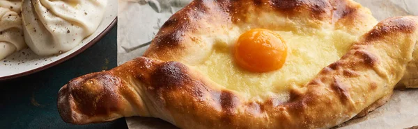 Khinkali and Adjarian khachapuri on baking paper, panoramic shot — Stock Photo