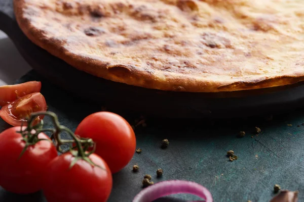 Imereti khachapuri with tomatoes and spices on table — Stock Photo