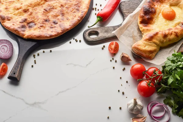 Imereti and adjarian khachapuri with vegetables and cilantro on marble texture — Stock Photo