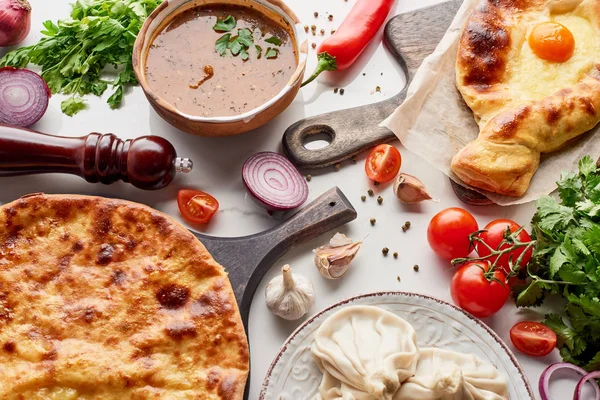 Adjarian and imereti khachapuri, soup kharcho and khinkali with vegetables and spices on marble texture — Stock Photo