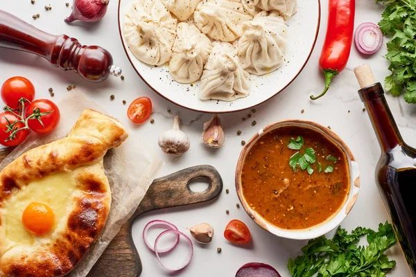 Adjarian khachapuri, Suppe kharcho, Weinflasche und khinkali auf Marmorstruktur — Stockfoto