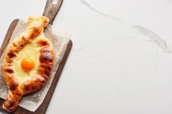 Top view of adjarian khachapuri on chopping board on marble texture — Stock Photo