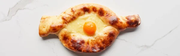 Top view of traditional adjarian khachapuri on marble texture, panoramic shot — Stock Photo