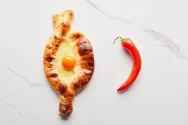 Vue du dessus du khachapuri adjarien avec du piment sur la texture du marbre — Photo de stock