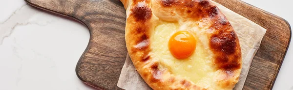 Top view of adjarian khachapuri on cutting board on marble texture, panoramic shot — Stock Photo