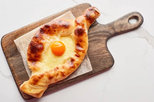 Top view of adjarian khachapuri on cutting board on marble texture — Stock Photo