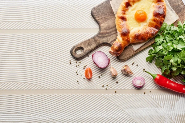 Top view of adjarian khachapuri with vegetables and cilantro on textured background — Stock Photo