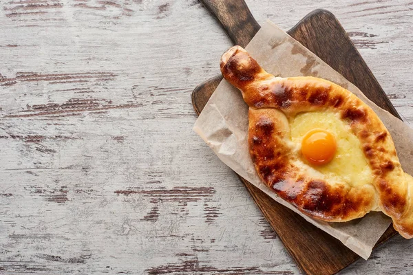 Top view of traditional adjarian khachapuri on cutting board on wooden texture — Stock Photo