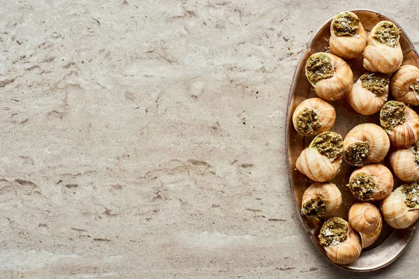 Vue de dessus de délicieux escargots cuits sur plaque sur fond de pierre — Photo de stock