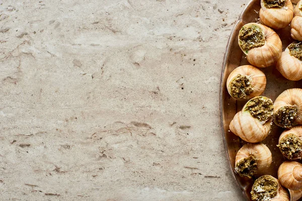 Vue de dessus de délicieux escargots cuits sur plaque sur fond de pierre — Photo de stock