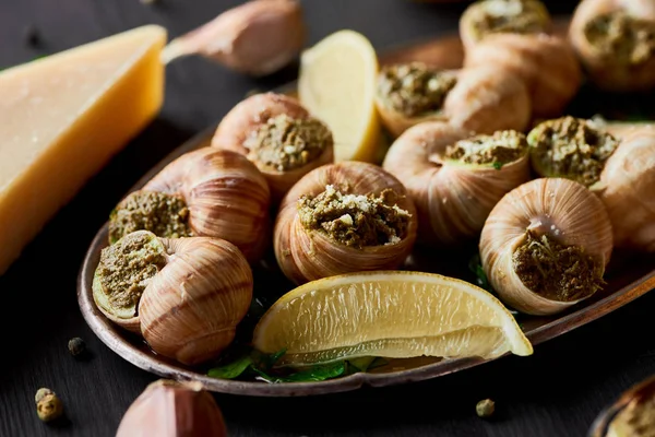 Close up view of delicious cooked escargots with lemon slices — Stock Photo