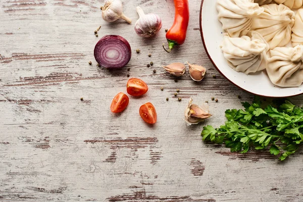 Vue du dessus de délicieux khinkali près des légumes et des épices sur une table en bois avec espace de copie — Photo de stock