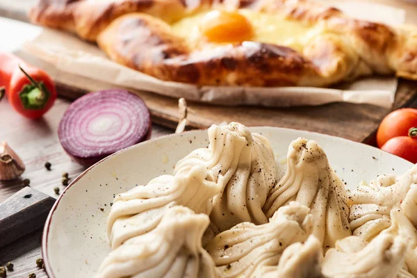 Selective focus of delicious khinkali and Adjarian khachapuri on wooden table — Stock Photo